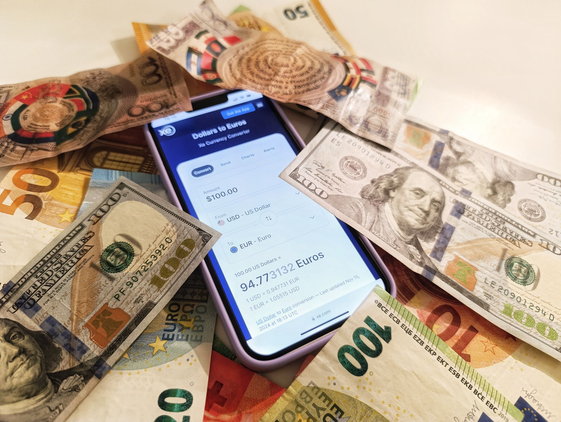 a mix of foreign currency notes and a phone showing a banking app a mix of foreign currency notes and a phone showing a banking app